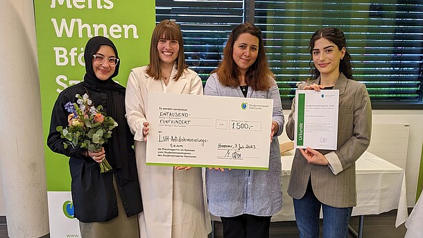 vier Studentinnen halten einen großen Check mit dem Preisgeld des Studentenwerks in Höhe von 1500,00 €   hoch